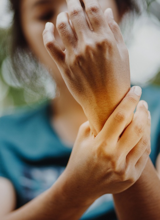 Woman suffering wrist pain due to autoimmune disorders, arthritis, or rheumatoid arthritis — part of holistic healing therapies for joint inflammation and chronic conditions like AVN, fibromyalgia, and ankylosing spondylitis.